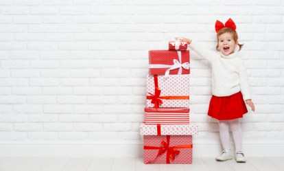 happy little girl child with Christmas gifts at a blank brick wall